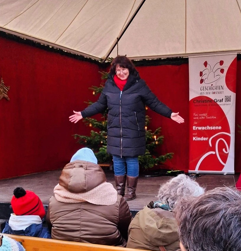 Märchenerzählerin Christine Graf bei einer Märchenreise für Kinder auf dem Christkindlmarkt Passau, Niederbayern; Live-Auftritt vor Publikum.